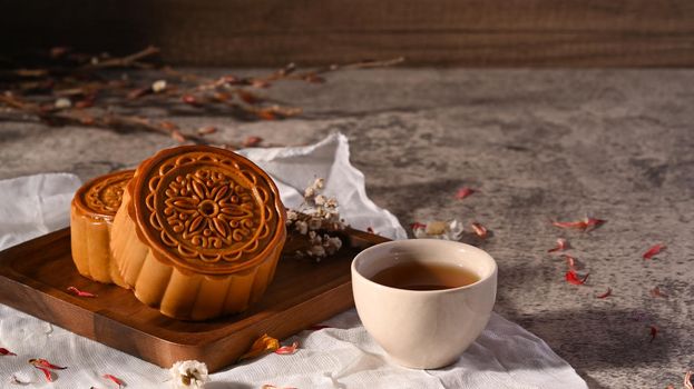 Delicious traditional mooncake and cup of tea on rusting stone table. Mid Autumn festival and Chinese traditional dessert.