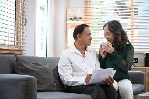 Happy senior couple relaxing on couch, spending time together in cozy living room.