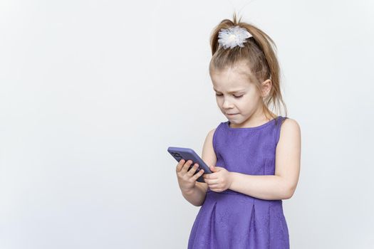 portrait of a cute 5 year old girl with a smartphone on a light background