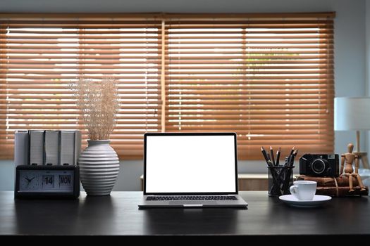 Mock up computer laptop with white screen on black tale in home office.