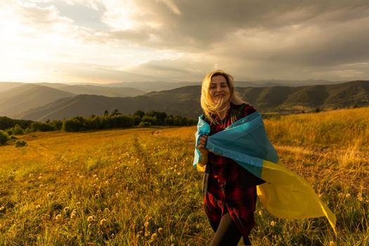 Woman holding a yellow and blue flag of Ukraine in outdoors. Independence Day. Flag Day. Constitution day. Woman in traditional embroidery with flag of Ukraine