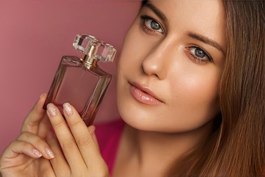 Perfume, beauty product and cosmetics model face portrait on pink background, beautiful woman holding fragrance bottle with floral feminine scent, fashion and makeup concept