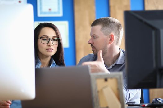 Business persons communicate in office at workplace in front of computer. Discussion of joint business project concept