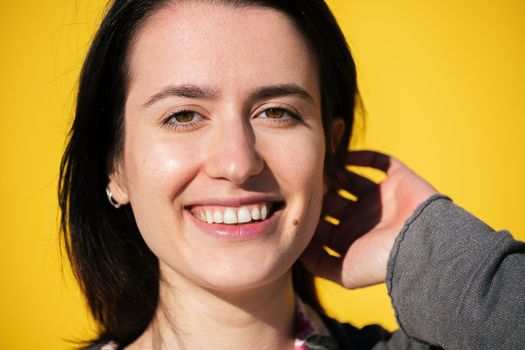 portrait of a happy young girl smiling with a yellow background, concept of protection against covid pandemic, concept of happiness and optimism