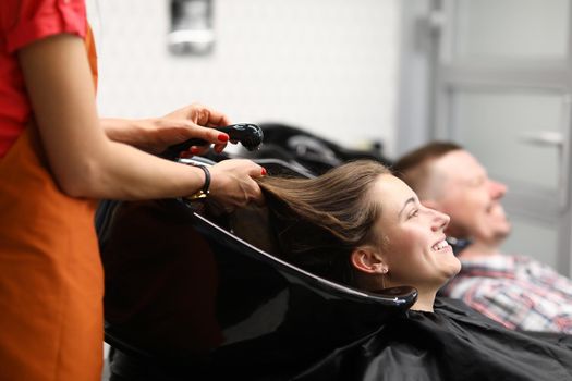 Beautiful happy smiling woman, professional hairdresser washes hair. Charming woman preparing her hair for new haircut concept