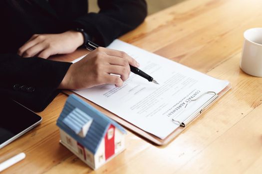 Asian female bank employee asking a customer to read the contract before signing to agree to buy a house, real estate concepts.