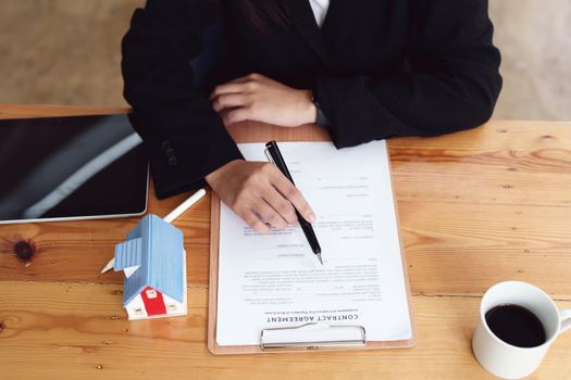 Asian female bank employee asking a customer to read the contract before signing to agree to buy a house, real estate concepts.