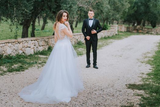 Happy stylish smiling couple walking in Tuscany, Italy on their wedding day. The bride and groom walk down the street by the hands. A stylish young couple walks. Husband and wife communicate nicely. Lovers run through the streets of the city.