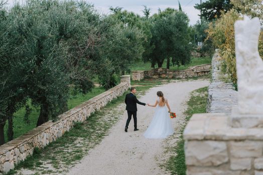 Happy stylish smiling couple walking in Tuscany, Italy on their wedding day. The bride and groom walk down the street by the hands. A stylish young couple walks. Husband and wife communicate nicely. Lovers run through the streets of the city.