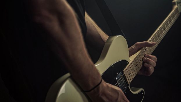 A guitarist plays an acoustic guitar with details of his hand and guitar strings