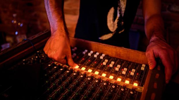 Man's hands on an old mixing console lights glowing obsolete music instruments detail