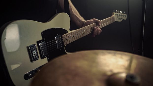 A guitarist plays an acoustic guitar with details of his hand and guitar strings