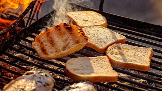 Pieces of white bread are grilling on the open fire outside, grill and barbecue, bbq at the countryside, cooking food, cooking on the fire, flame and coal