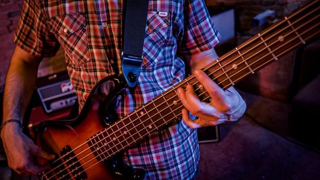 A male bass player plays a bass during a live performance on the stage