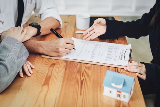 A spouse entering a home contract is reading the terms of the loan interest agreement that the bank officer or real estate agent is offering before signing.