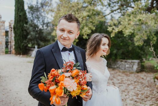 Happy stylish smiling couple walking in Tuscany, Italy on their wedding day. The bride and groom walk down the street by the hands. A stylish young couple walks. Husband and wife communicate nicely. Lovers run through the streets of the city.