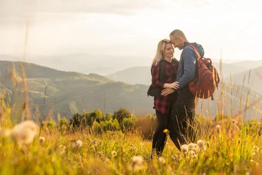 Happy traveler young couple resting in the mountains at sunset in spring or summer season