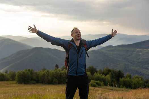 Young man enjoying the view on the top of the mountain. Carpathian mountains, Ukraine.