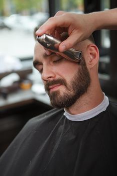 Vertical close up of a man getting his beard trimmed by professional barber