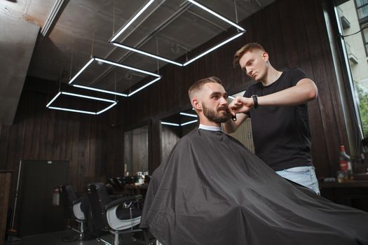 Attractive young man getting new haircut at the barbershop, copy space