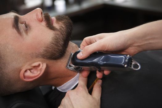 Cropped close up of a handsome bearded man getting his beard styled at the barbershop