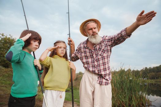 Senior man teaching his grandkids about fishing, looking strict and serious