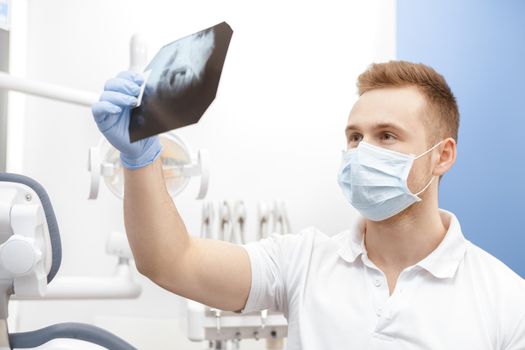 Modern technologies. Professional dentist examining dental x-ray of jaw and teeth at his office doctor professional occupation job specialist healthcare medicine experience qualified dentistry concept