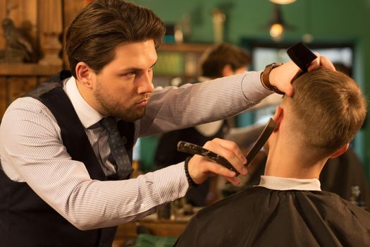 Young handsome bearded professional barber shaving his male client with a razor copyspace profession occupation vintage retro traditional classic barbershop barbering hairdresser job shave beard.