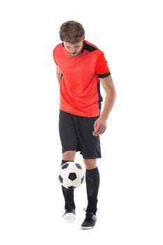 Full length portrait of a soccer player in red uniform kicking a ball isolated on white background