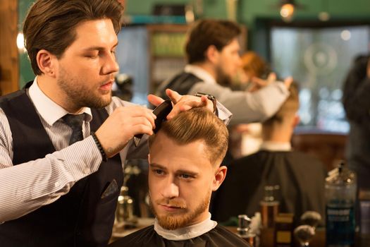 Handsome young man smiling getting a new haircut by a professional barber at the barbershop copyspace customer client service job styling hairdresser hipster masculinity grooming fashion.