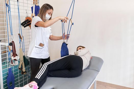 Physiotherapist with facial mask working with a patient lying on a stretcher