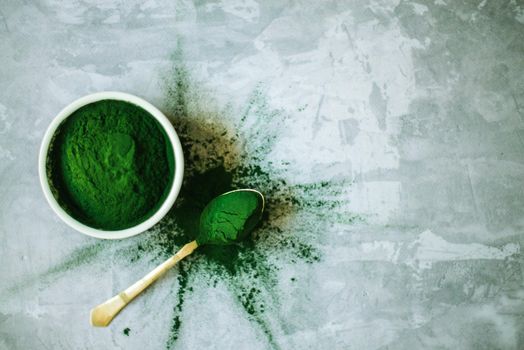 spirulina powder in white plate on concrete background. High quality photo