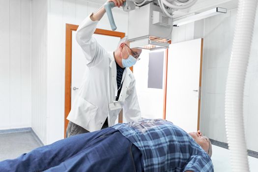 Male doctor checking a patient using a x-ray machine in a hospital room