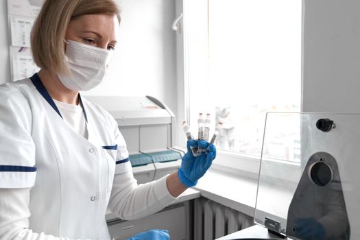 Doctor with a protective mask holding a raw of samples while using a centrifuge in an hospital