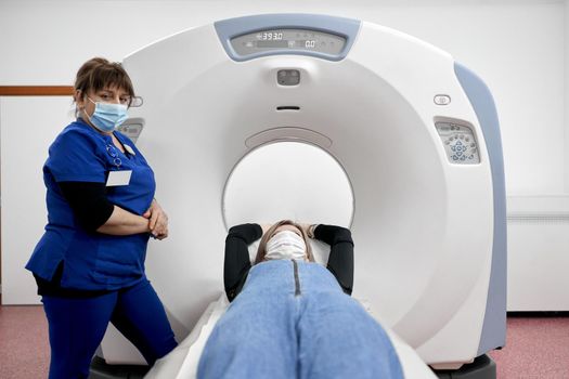 Frontal view of a patient into a ct scan machine next to a doctor in an hospital