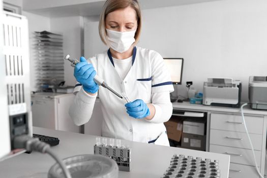Hospital laboratory technician working with samples and a centrifuge reaction vessel in a lab