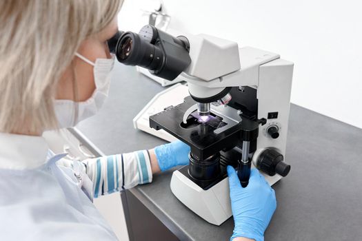 Close up view of female scientist using a microscope in a laboratory of an hospital