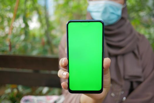 young women with face mask showing using smart phone with green screen ,