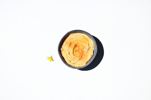 Flat lay. Overhead view. Food still life of traditional oriental meal- a chickpea hummus with sprinkled paprika peppers in blue ceramic bowl, isolated on white background with copy ad space for text
