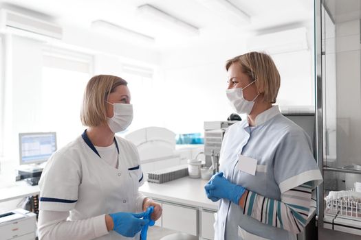 Two female doctors with facial mask chatting in a hospital