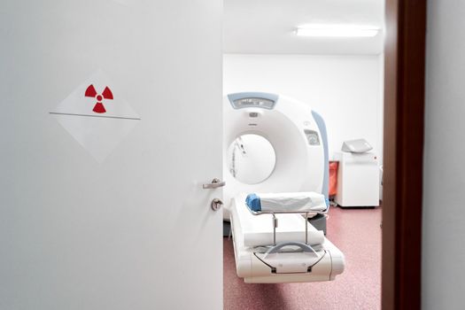 Machine to take a tomography scan in a hospital next to symbol of radioactivity