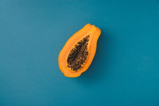 single papaya fruit cutter on half on blue background. copy space