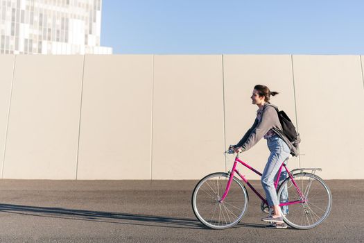 happy young woman riding a pink retro bike, concept of active lifestyle and sustainable urban mobility