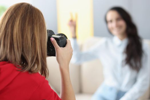 Woman photographer photographs model on camera at home. Photographer services and home shooting concept