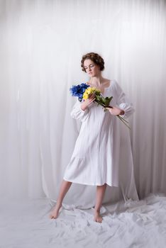 Caucasian Ukrainian teenager stand in the studio in a dress and yellow-blue flowers on a white background . Concept - Stop the war in Ukraine. A free Ukrainian, an invincible nation