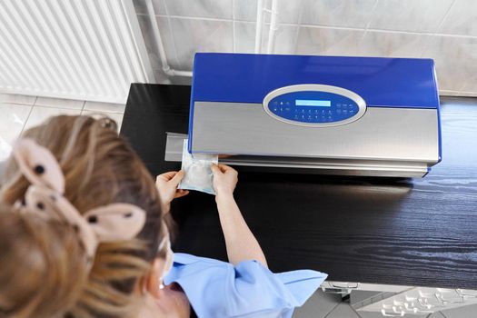 Top view of a nurse using a heat-sealing machine to seal a bag with material in an hospital