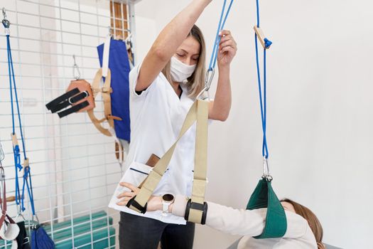 Physiotherapist using a sling to immobilize an arm during rehabilitation therapy with a patient