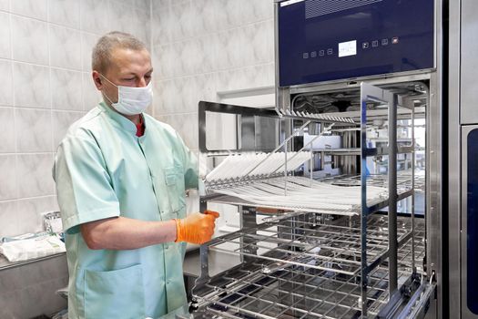 Worker wearing gloves using a machine to sterilising medical supplies in an hospital