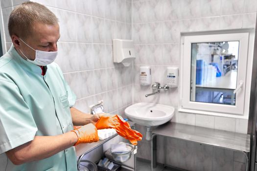 Man putting on gloves while using a machine to sterilising the medical supplies of an hospital