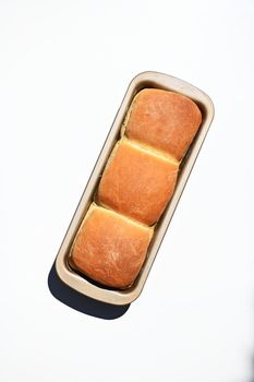 Top view of a baking dish with freshly baked hot whole grain bread, isolated on white background with copy ad space for advertising text. Still life. Food composition. Flat lay